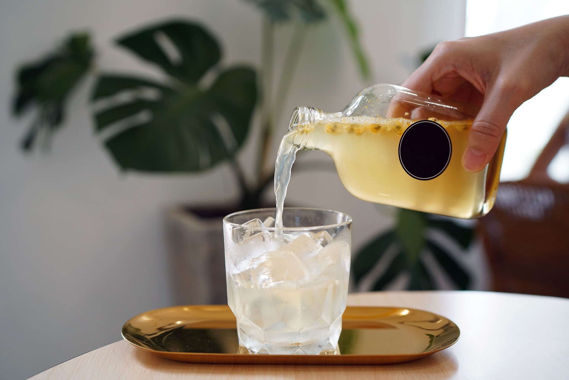 Iced passion fruit soda - Pouring fresh juice into a glass on wooden table and blurred background, Perfect drink for summer time.