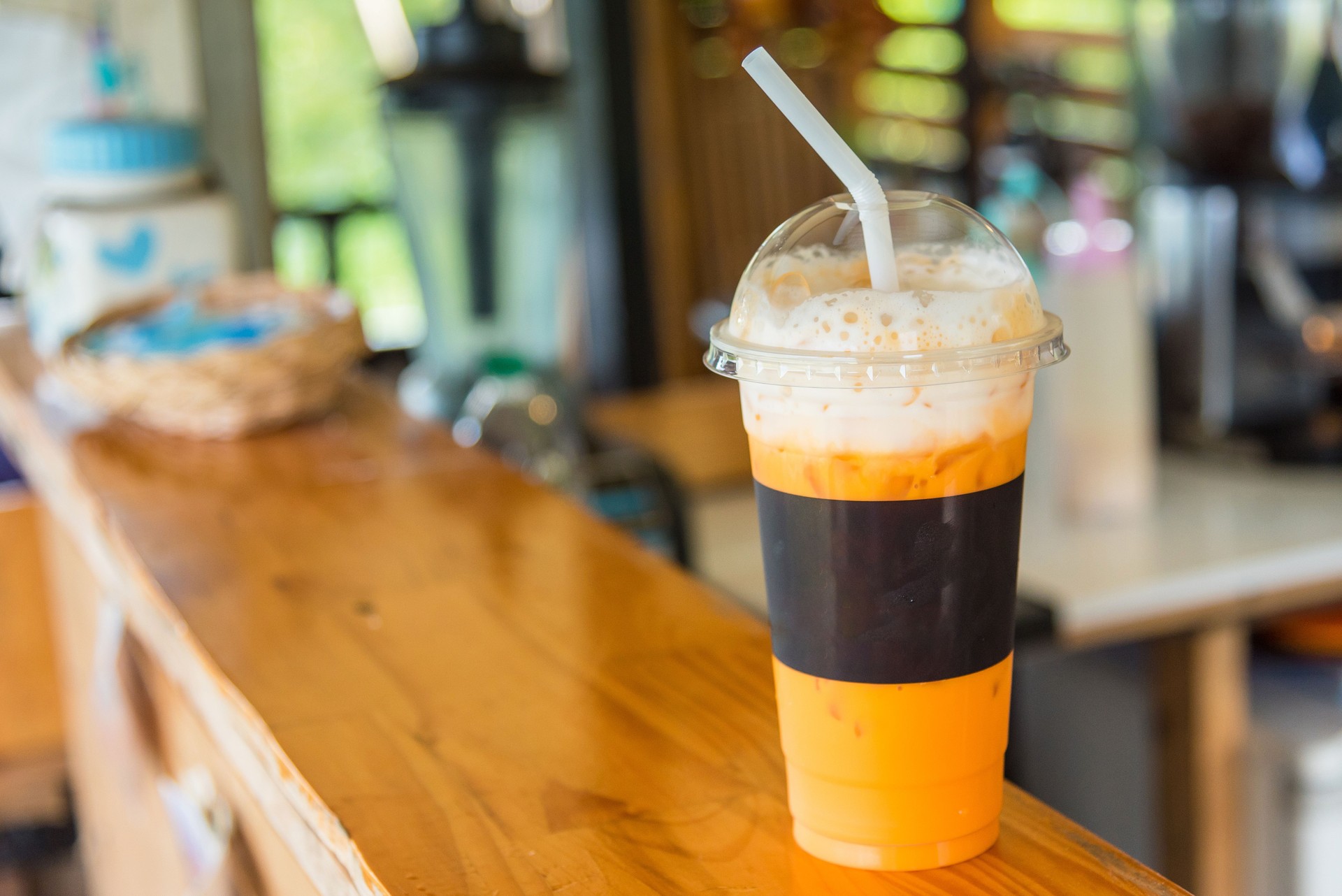 The sweet cooled thai tea drink with ice on shop counter background.
