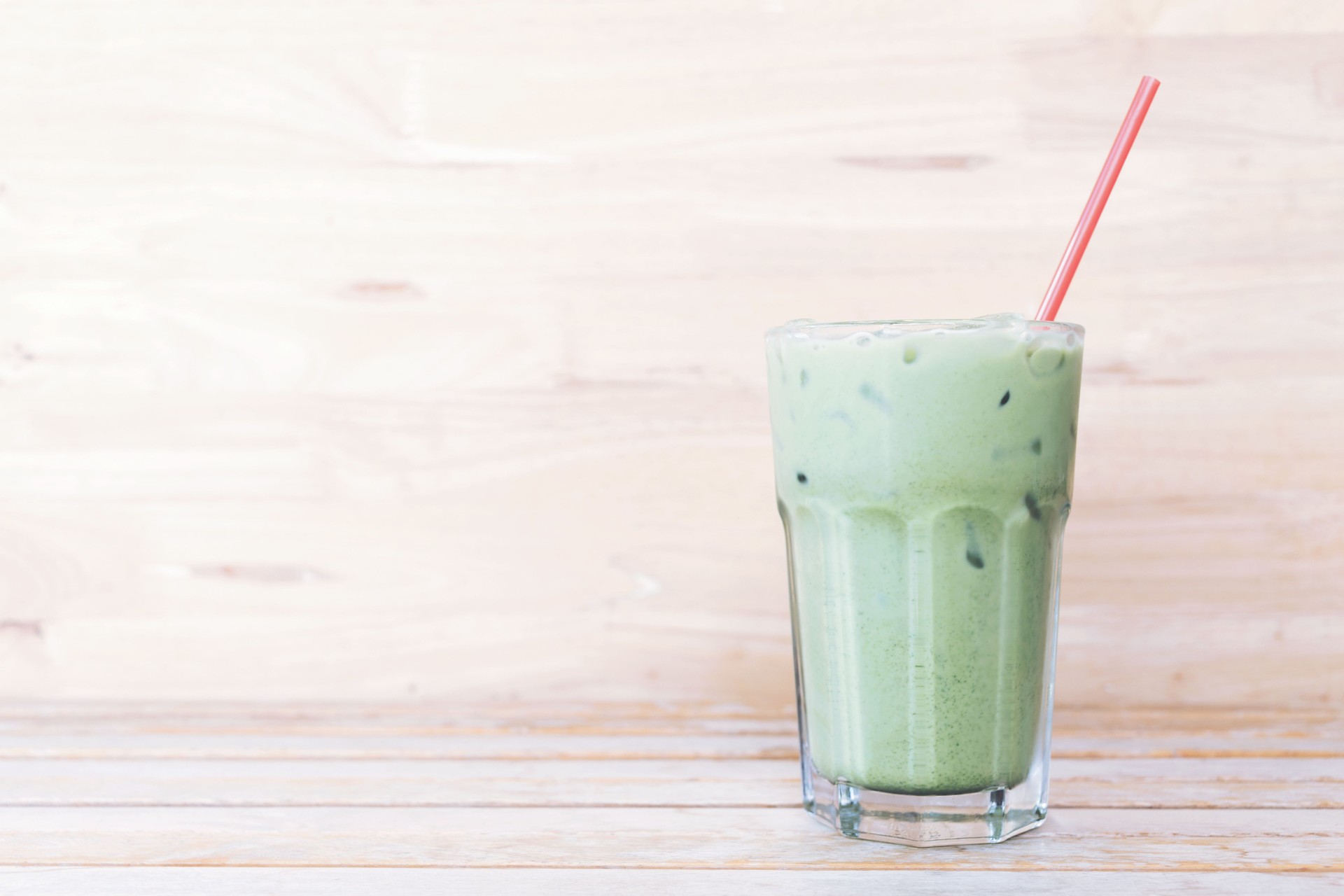 ice green tea (matcha)with a red straw on wood background