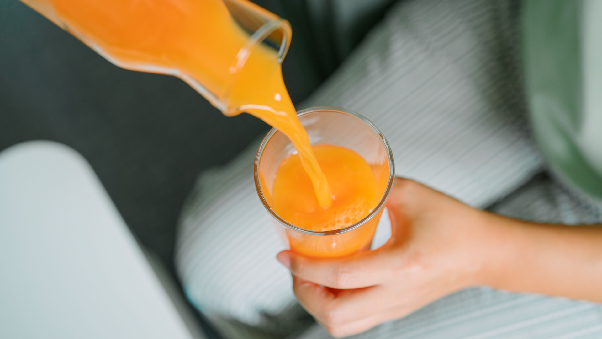 Asian woman pouring orange juice in to the glass