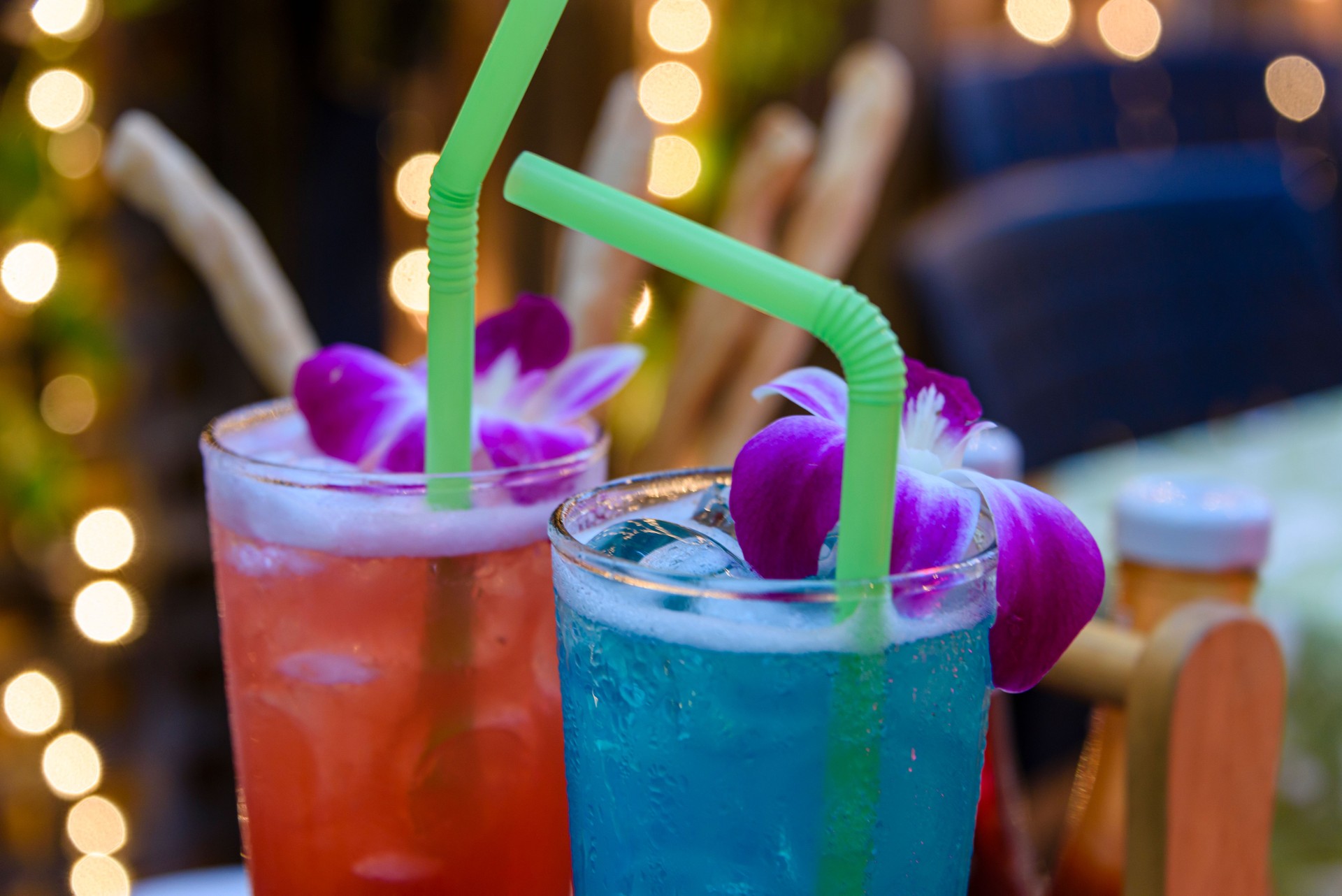 Red and blue cocktails with straws and purple flowers in a bar